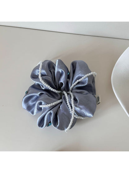 Multiple Gifty satin scrunchies in various colors displayed on a white surface
