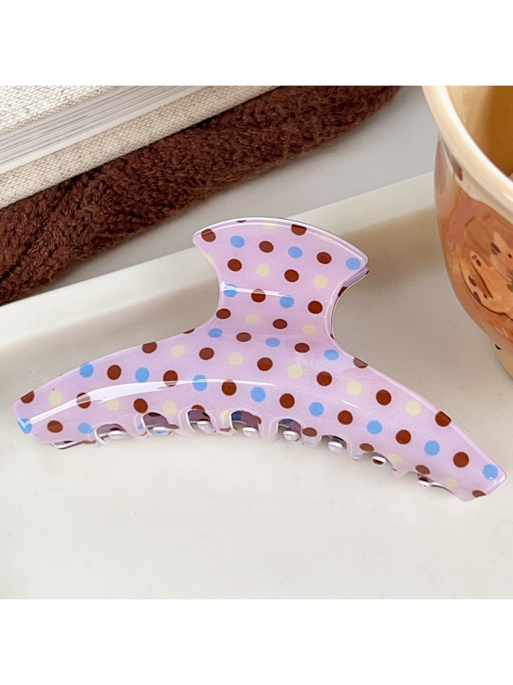 Beau crescent shaped pink claw clip with white polka dots displayed on a flat surface