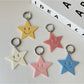 Stylish five pointed star keychain hanging from a black leather bag zipper