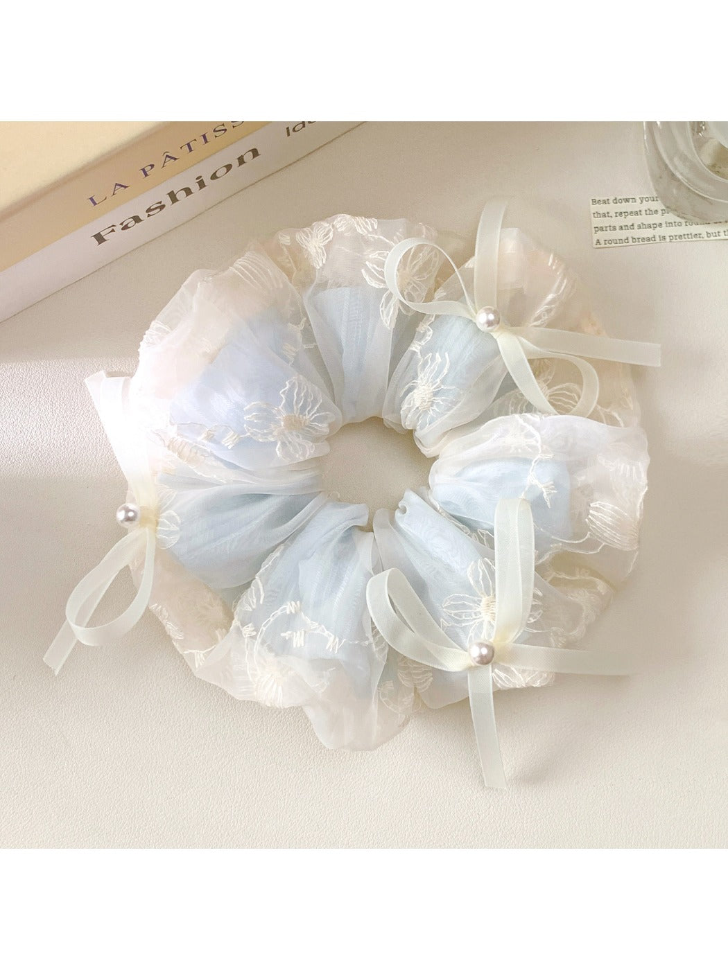 Close-up of Gifty scrunchie with a cute bow embellishment in soft pink fabric