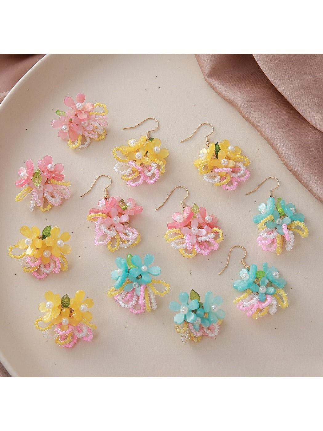 Close-up of small colorful beaded flower cluster earrings on white background