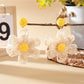 Pair of raffia flower drop earrings hanging from a jewelry stand