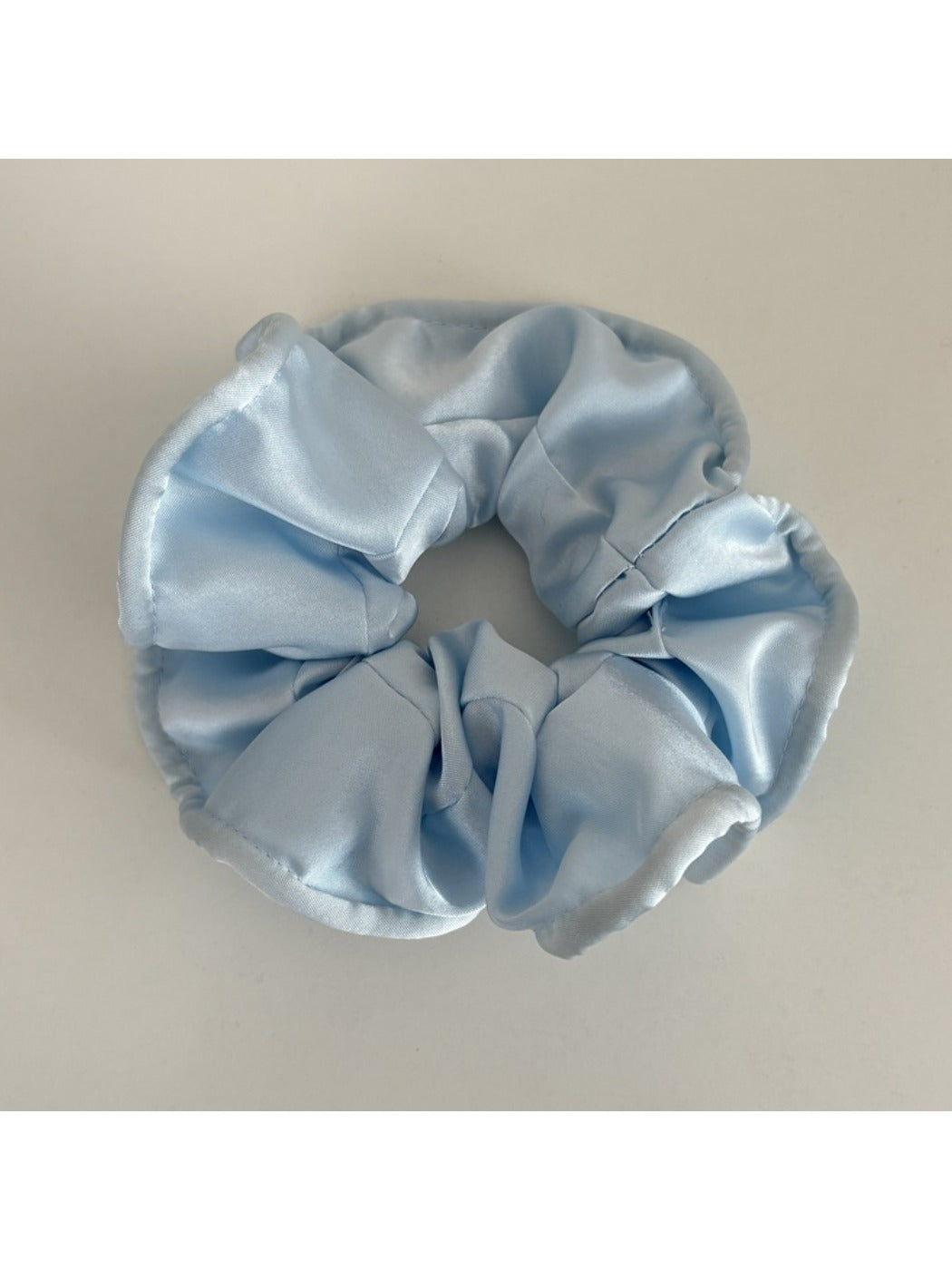 Gifty satin scrunchie in soft pink placed next to matching hair accessories