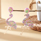 Flamingo earrings placed on a textured surface with natural lighting