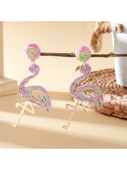 Flamingo earrings placed on a textured surface with natural lighting