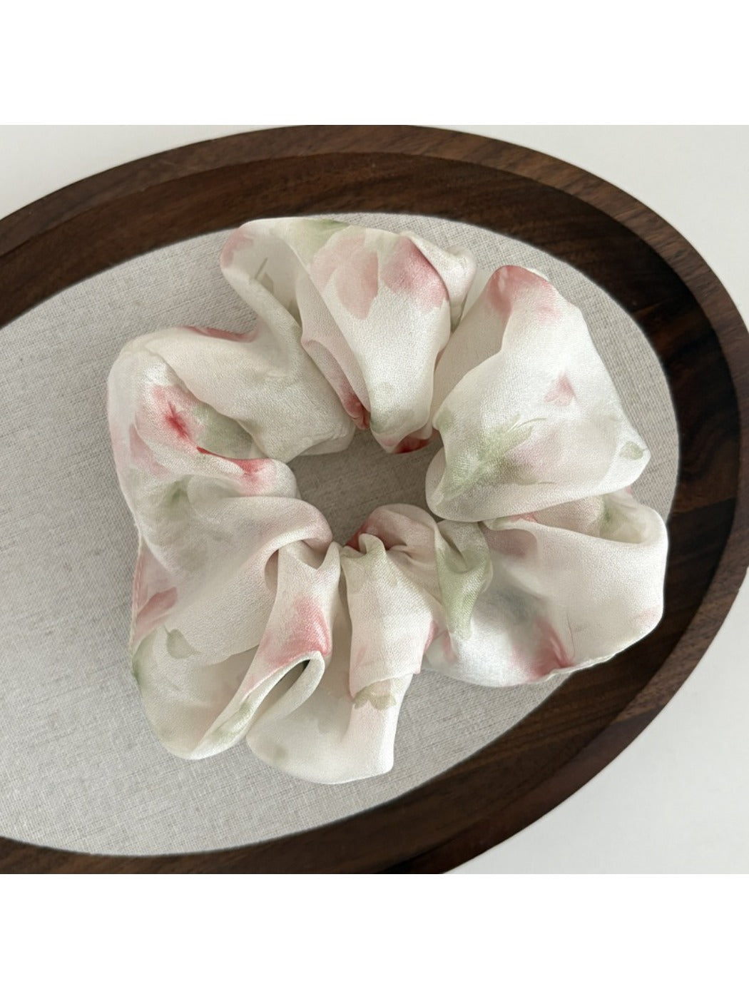 Model styling hair with Gifty printed satin scrunchie in a casual outfit