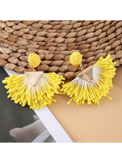 Earedge fan-shaped raffia earrings hanging from a jewelry stand