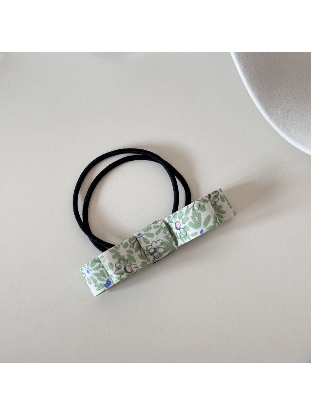 Hair tie with a cute pink bow held in hand showing size and detail