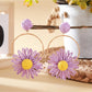 Earedge raffia circle flower earrings hanging on a jewelry stand