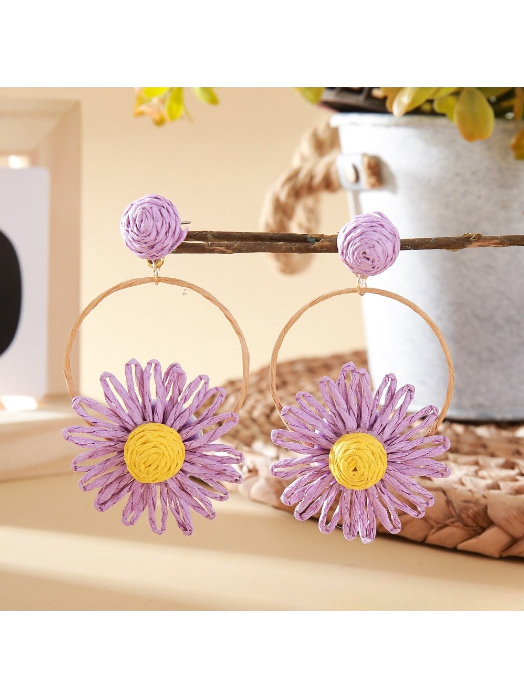 Earedge raffia circle flower earrings hanging on a jewelry stand