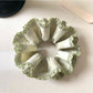 Green double layer scrunchie worn on a wrist as a stylish accessory