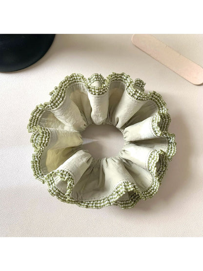 Green double layer scrunchie worn on a wrist as a stylish accessory
