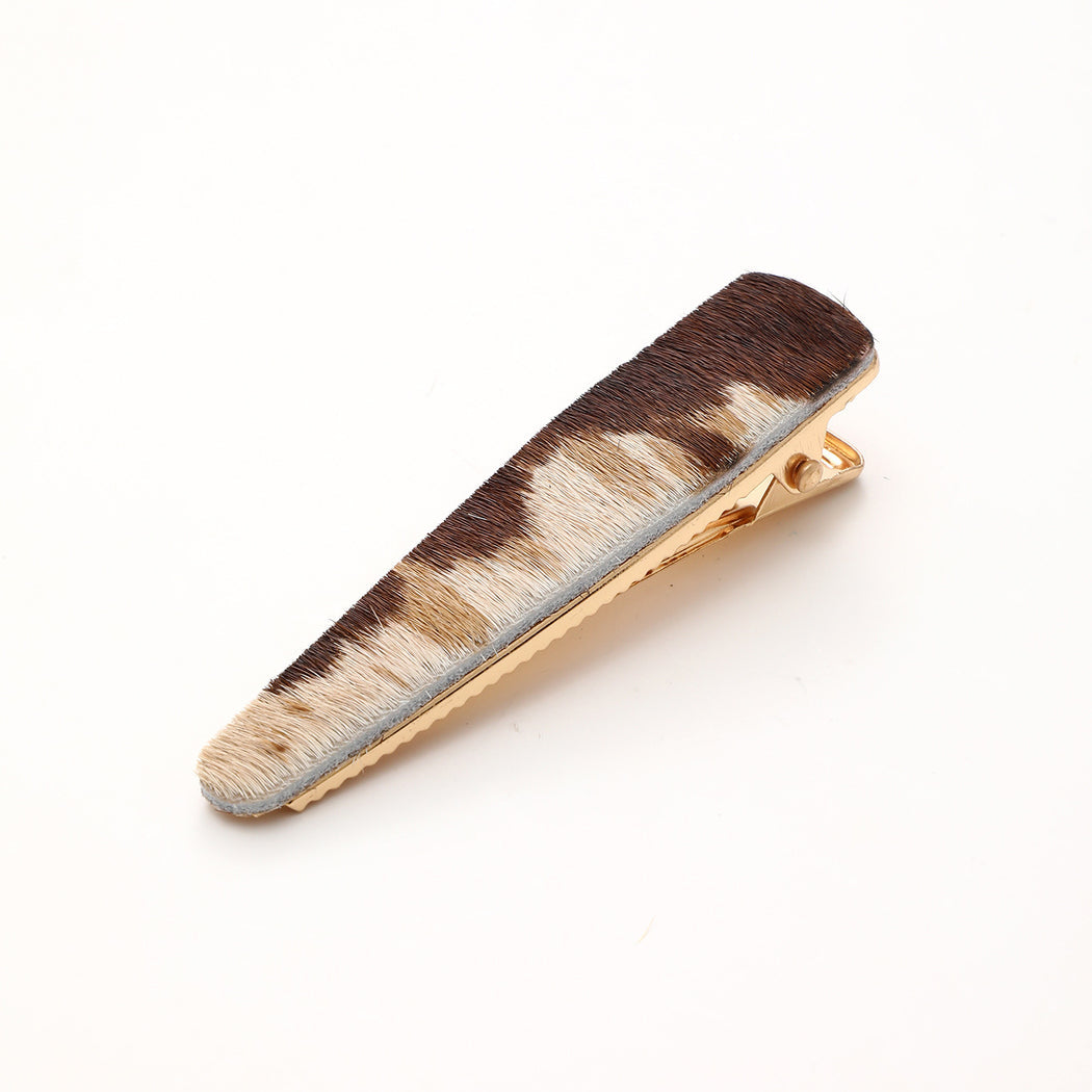 Brown and white cow print elongated barrette on white background
