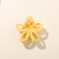 Beau hair clip attached to a ponytail, featuring a vibrant flower shape