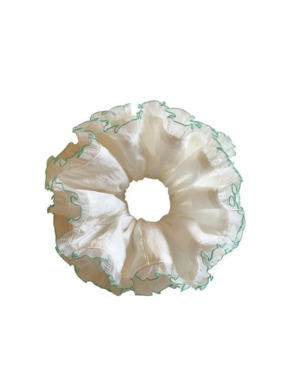 White tulle double scrunchie with green trim displayed on a hand