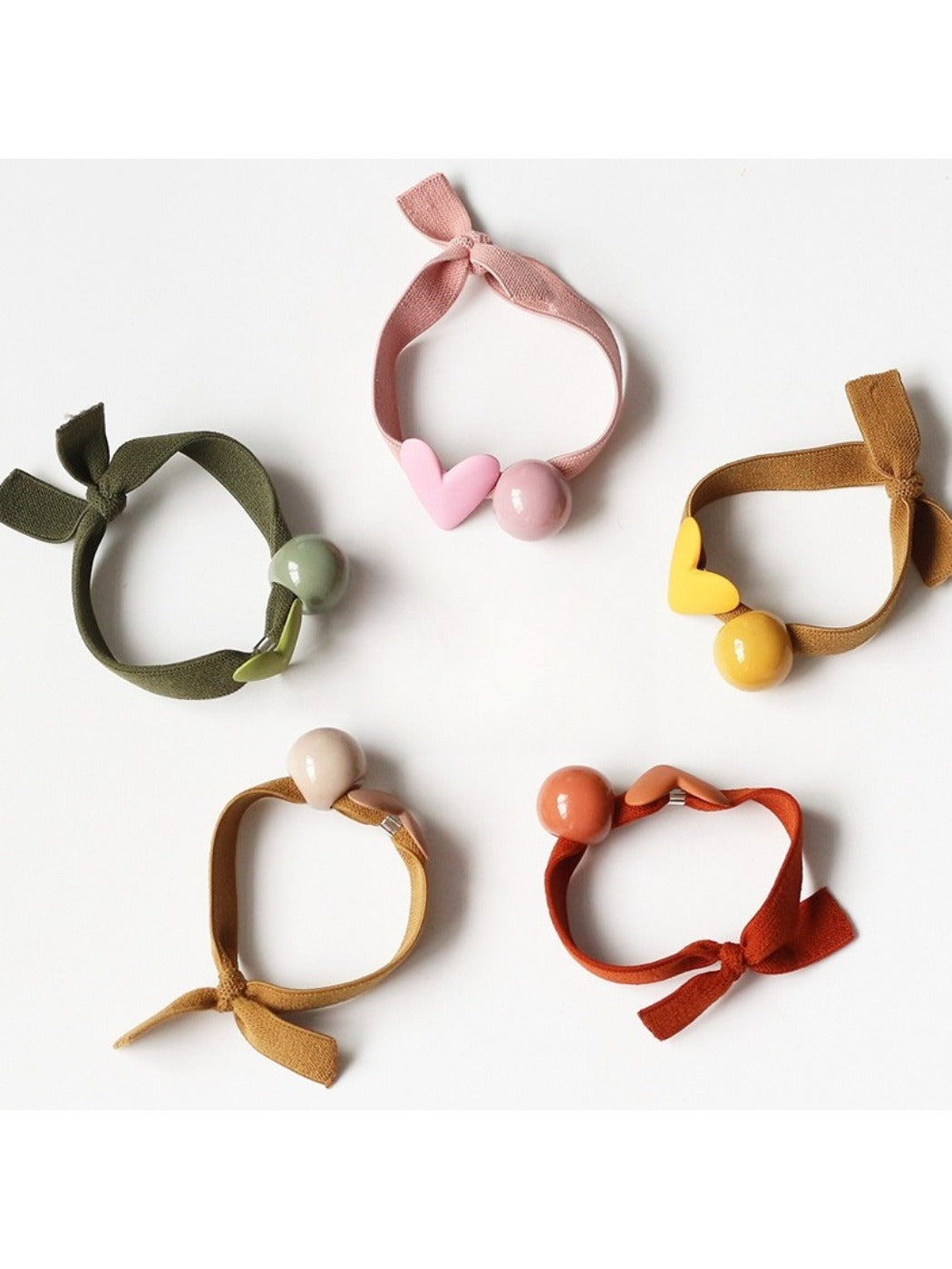 Set of colorful hair ties with small heart decorations on a white background