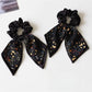 Close-up of Gifty printed bow hair tie with floral pattern on a white background