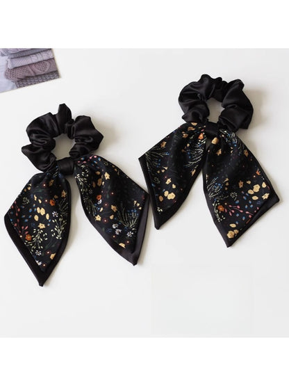 Close-up of Gifty printed bow hair tie with floral pattern on a white background
