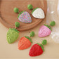 Close-up of raffia woven strawberry-shaped earrings with green leaf details
