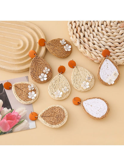Earedge raffia teardrop earrings hanging on a wooden display stand
