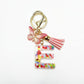 Butterfly and letter keychain displayed with other accessories on a table