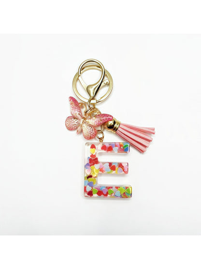 Butterfly and letter keychain displayed with other accessories on a table