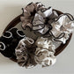 Side view of pink ruffled satin scrunchie showing fabric folds and sheen