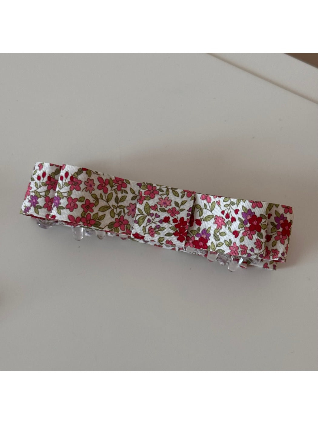 Beau pink floral hair clip held in hand showing size and details