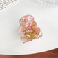 Beau Sweet Rose hair claw clip with pink rose decoration held against a neutral background