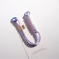 Minimalist colorful rope keychain coiled on a white surface
