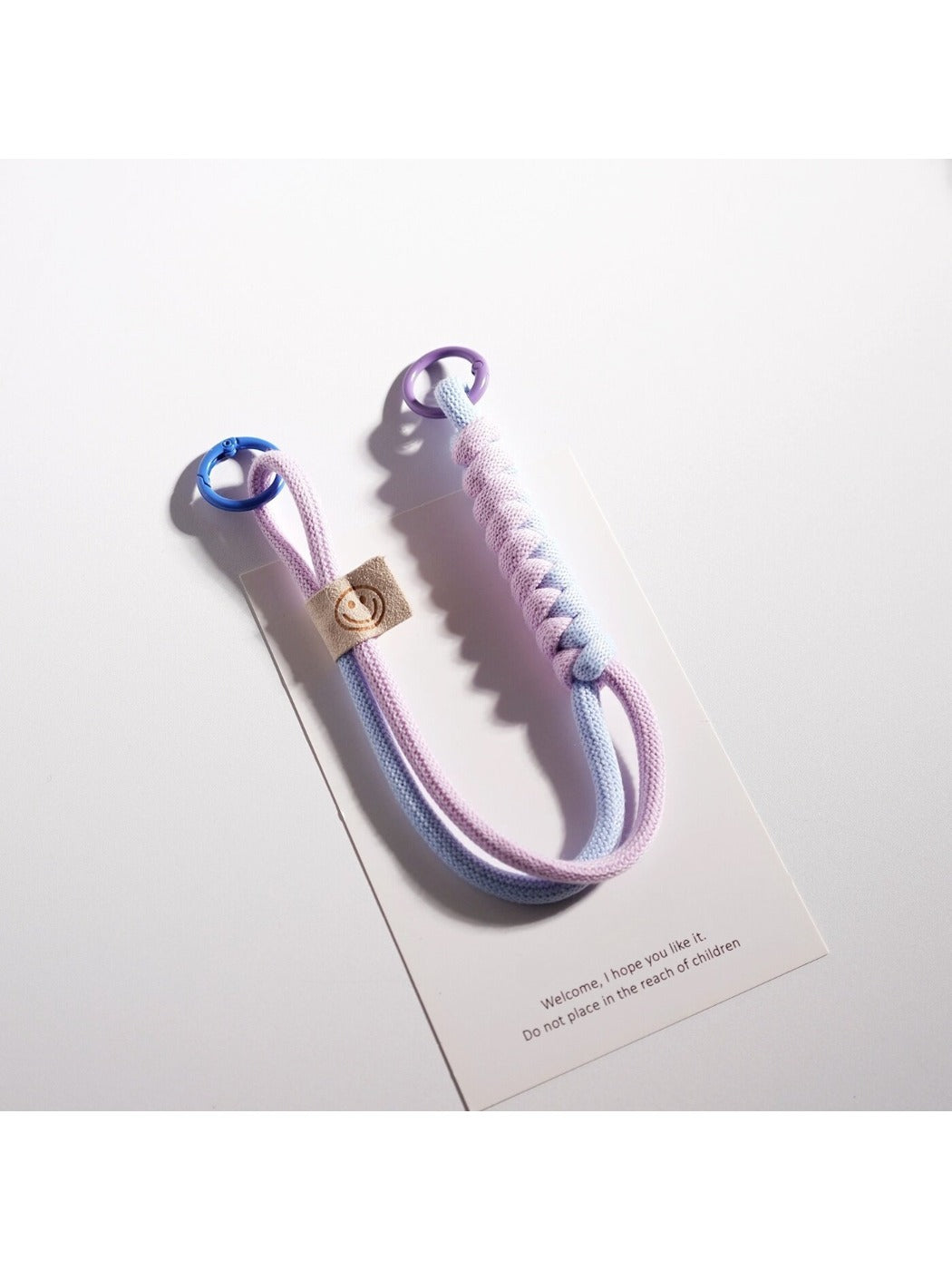 Minimalist colorful rope keychain coiled on a white surface