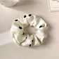 Gifty satin scrunchie styled on a wrist as a bracelet with polka dot pattern