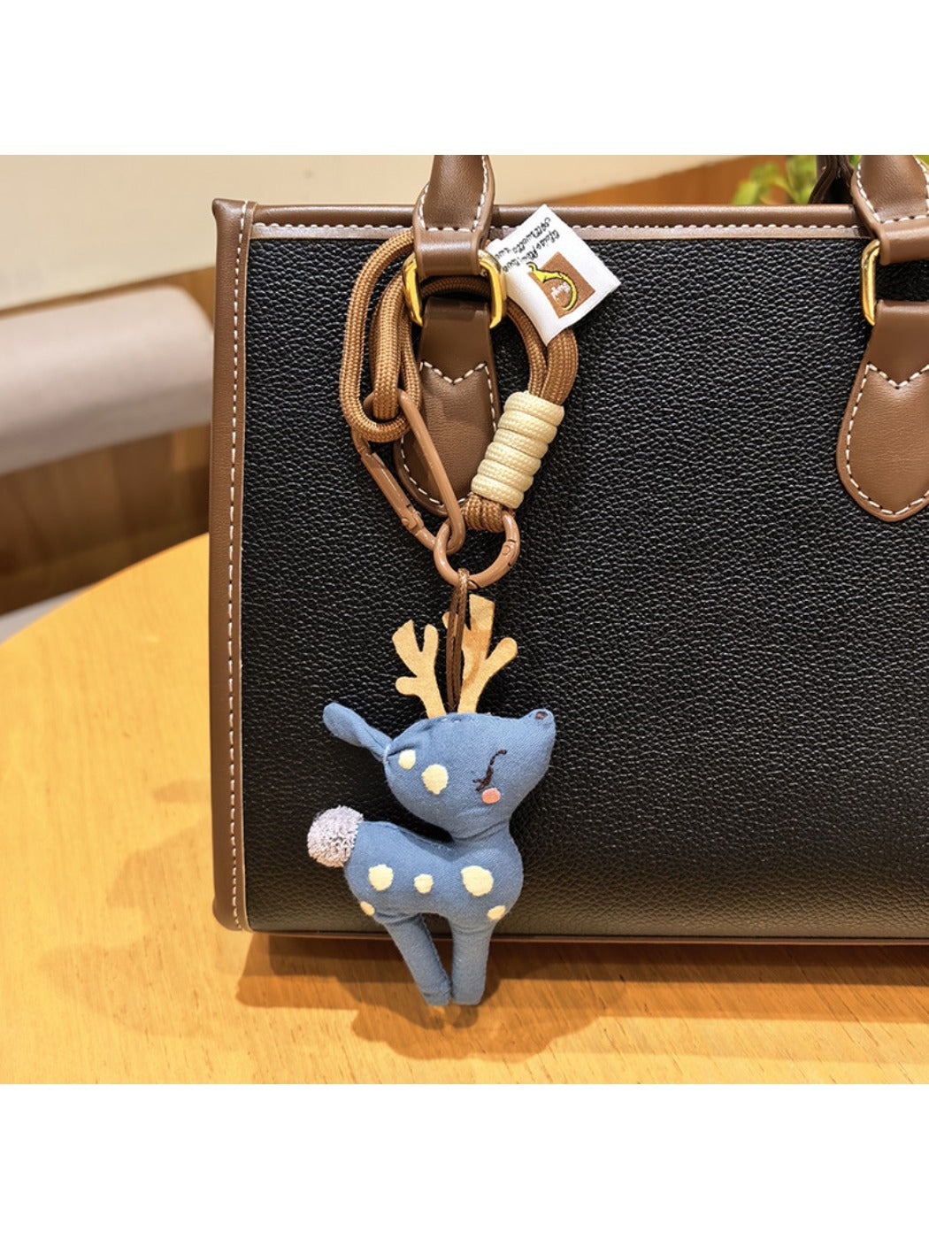Deer charm keychain resting on a rustic wooden table with natural light