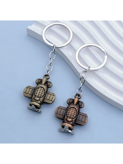 Airplane keychain hanging from a set of keys on a wooden surface