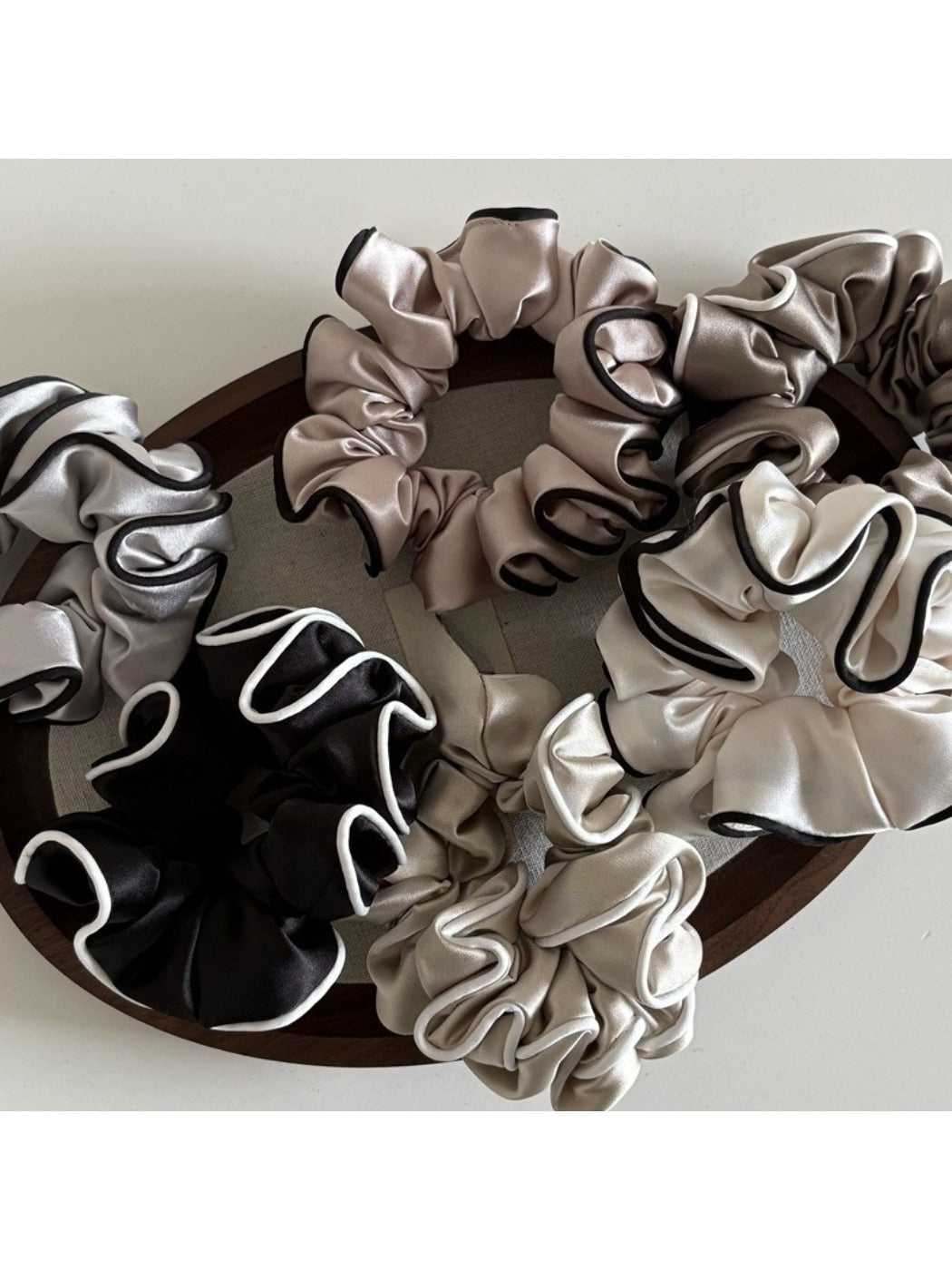 Close-up of Gifty ruffled fabric satin scrunchie in soft pink color