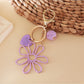 Raffia flower keychain displayed on a white background with metal keyring