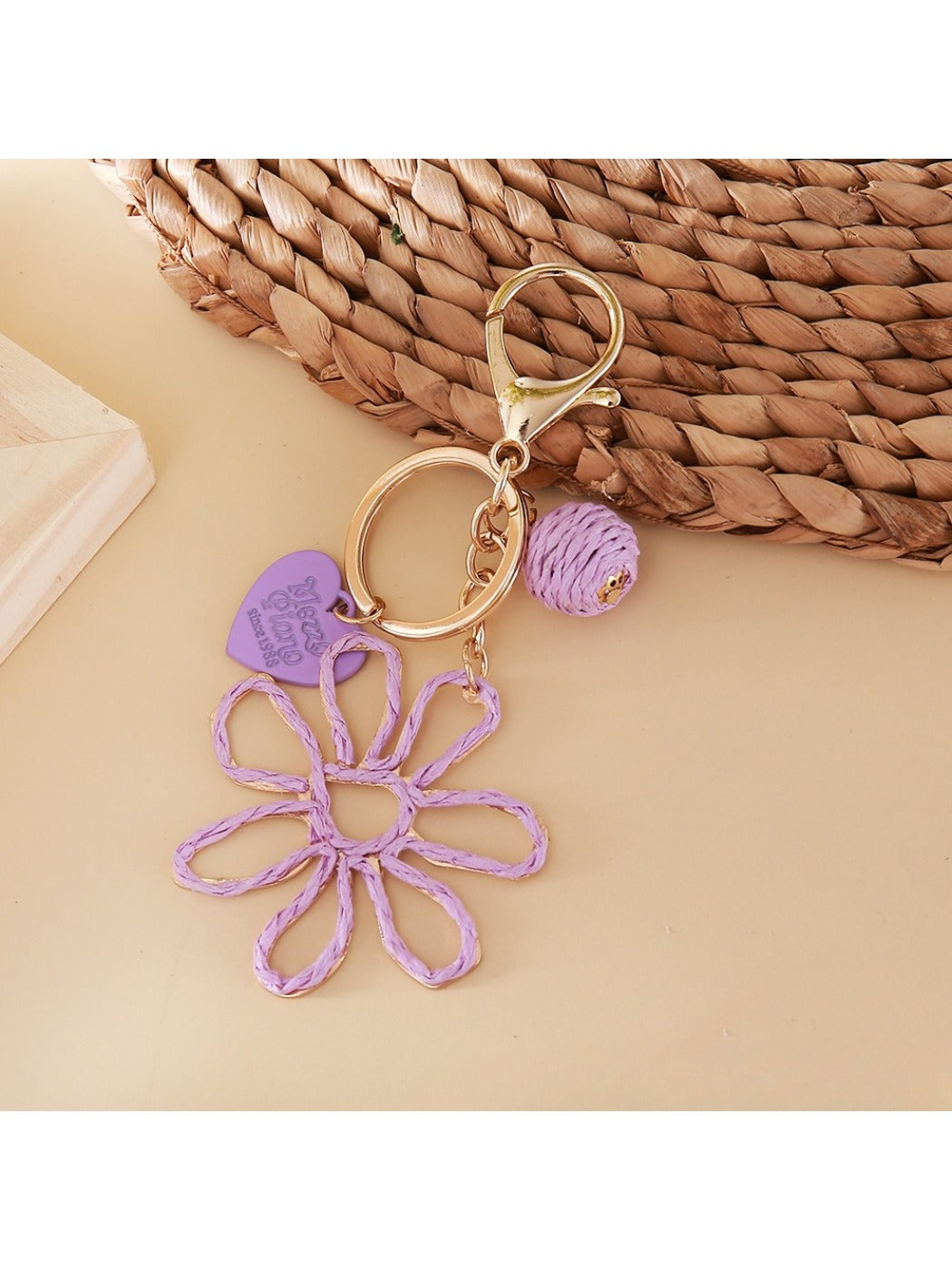 Raffia flower keychain displayed on a white background with metal keyring