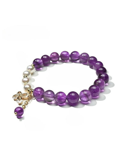 Detailed shot of butterfly charm on Lovra vintage beaded bracelet with multicolored beads