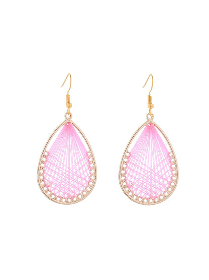 Pair of Earedge Cord Woven Teardrop Earrings on a wooden surface with soft lighting