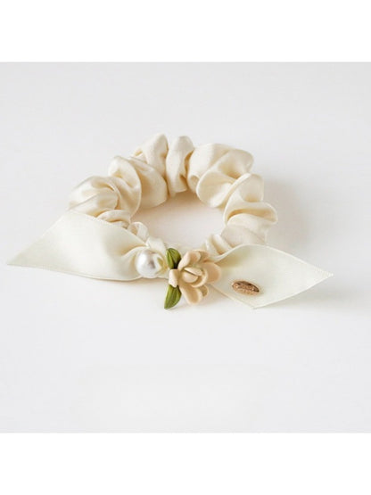 Gifty floral hair tie placed next to matching floral accessories on a wooden surface