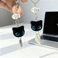 Black cat keychain with bright blue eyes hanging from a silver keyring