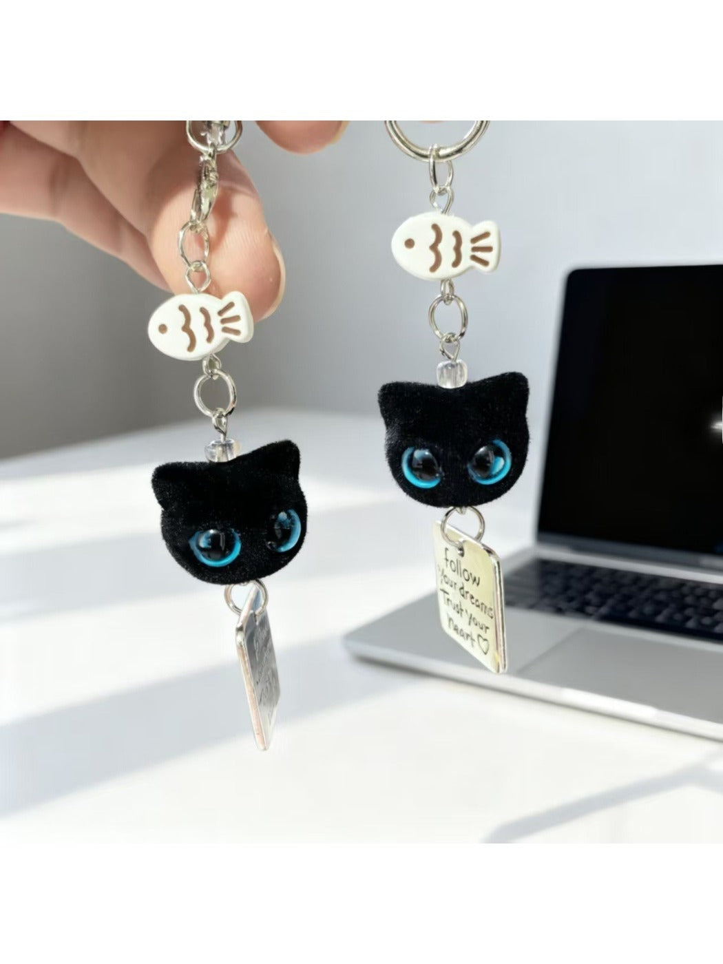 Black cat keychain with bright blue eyes hanging from a silver keyring