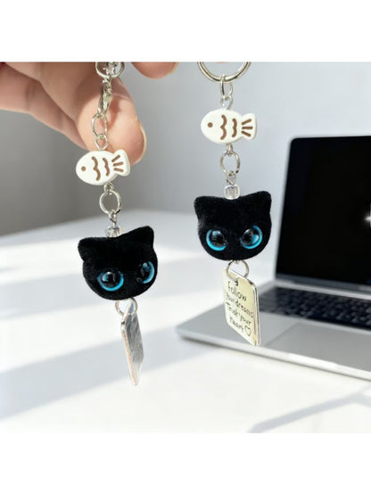 Black cat keychain with bright blue eyes hanging from a silver keyring