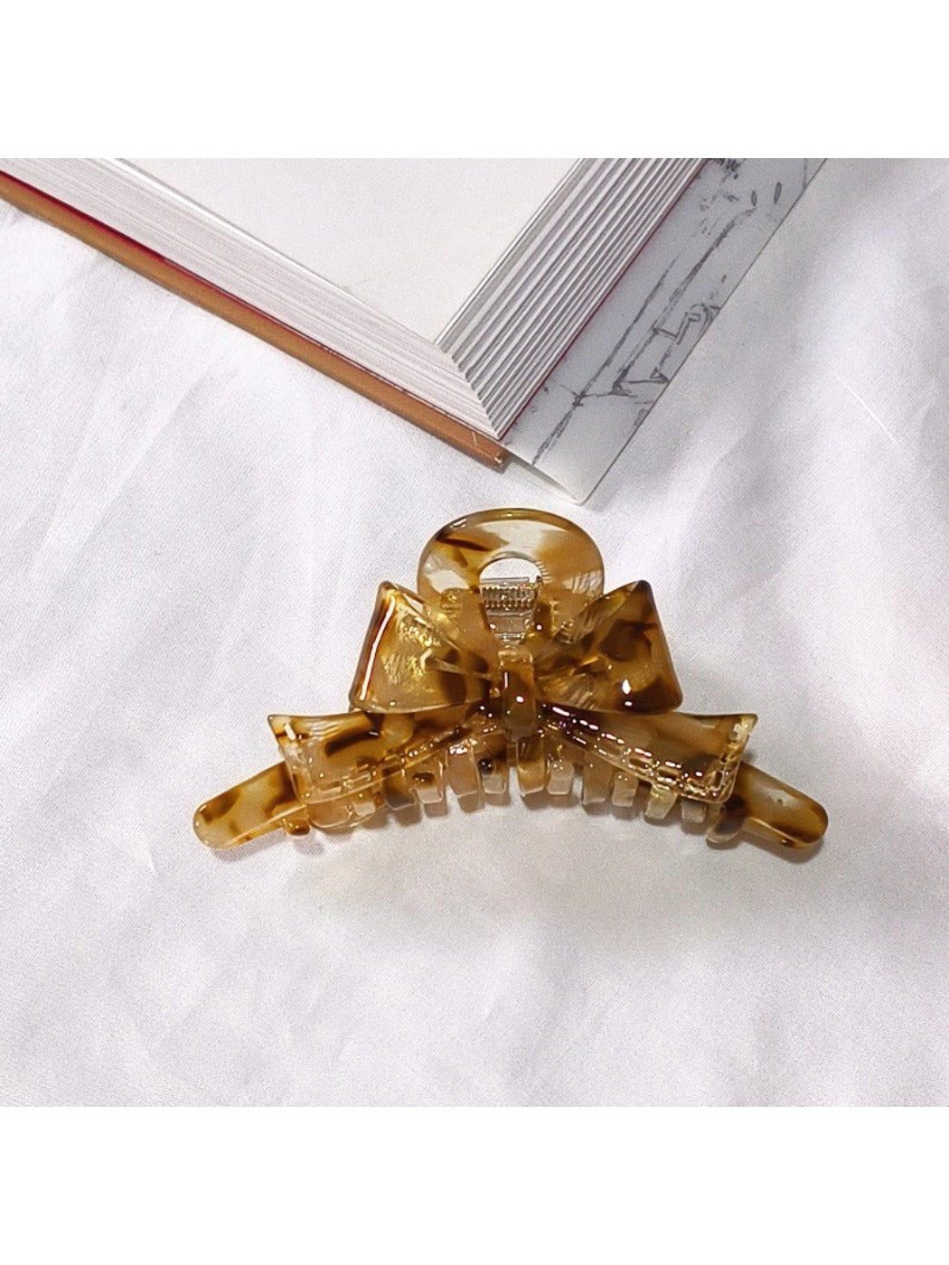 Beau acetate bow shaped claw clip shown with natural light highlighting color