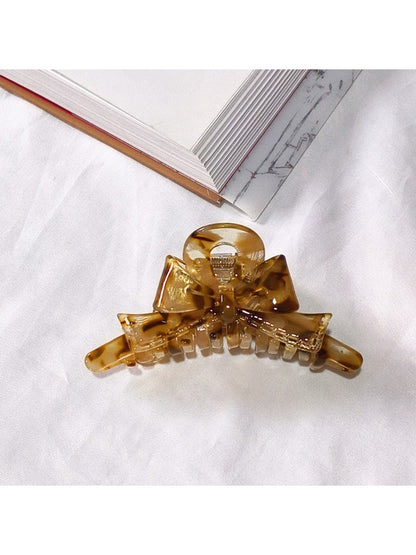 Beau acetate bow shaped claw clip shown with natural light highlighting color