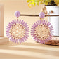 Sunflower drop earrings placed on a wooden surface with natural lighting
