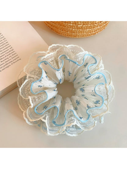 Gifty floral ruffled scrunchie styled on a wrist showing soft fabric texture and floral pattern