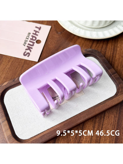Beau plastic square claw clip resting on textured fabric background
