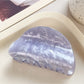 Beau crescent shaped claw clip displayed with pastel colored props
