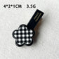 Beau acrylic hair clip shown clipped in brown hair with flower and heart accents